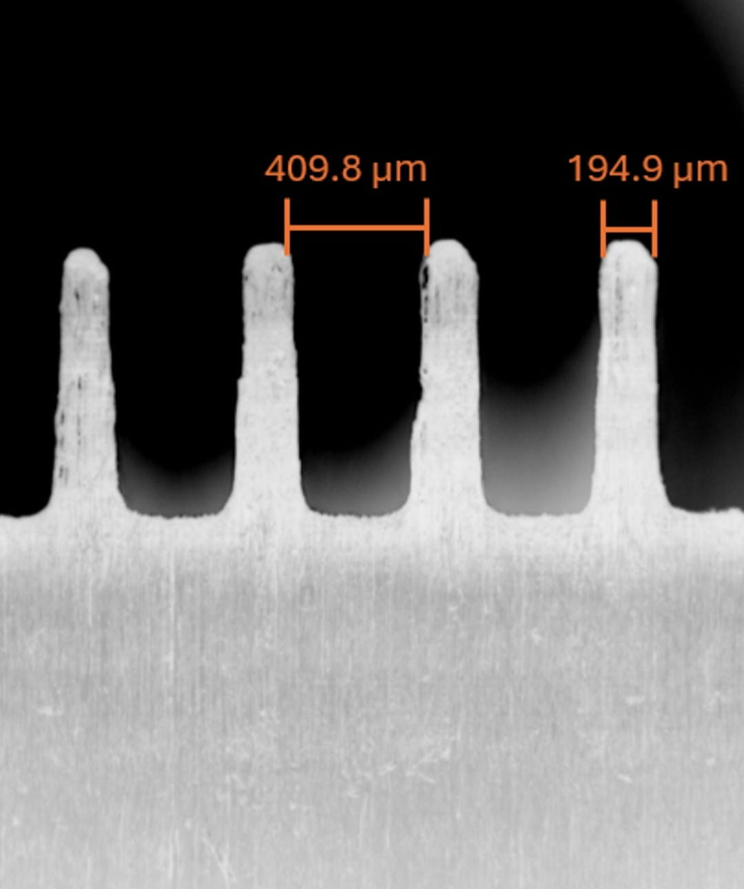 SEM image of 3D-printed microfluidic channel pillars with feature spacings of 409.8 and 194.9 micrometres labelled